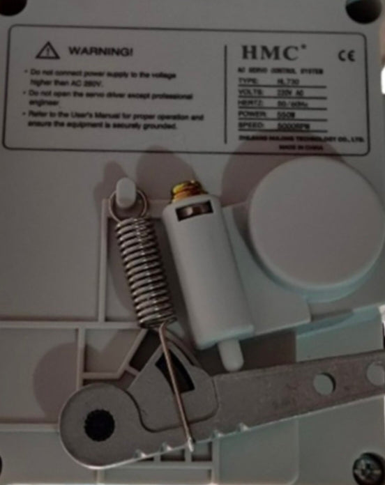 Close-up of a mechanical device with HMC branding and warning label.