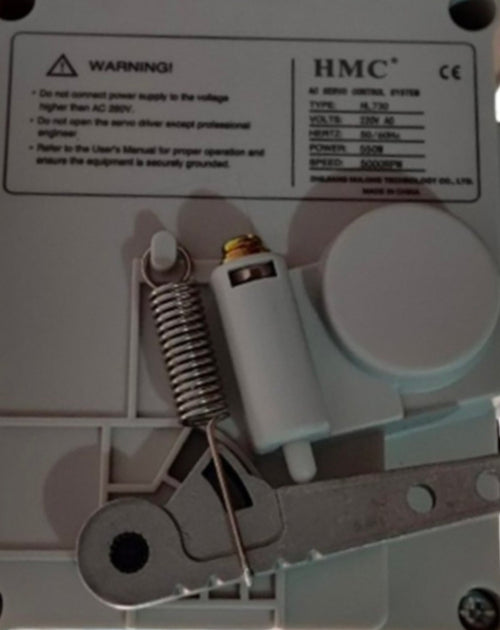 Close-up of a mechanical device with HMC branding and warning label.